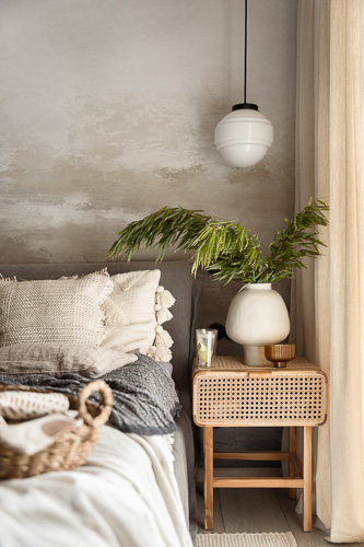 ratanowy boho stolik nocny z ozdobami i wazon z roslinami w przytulnej sypialni