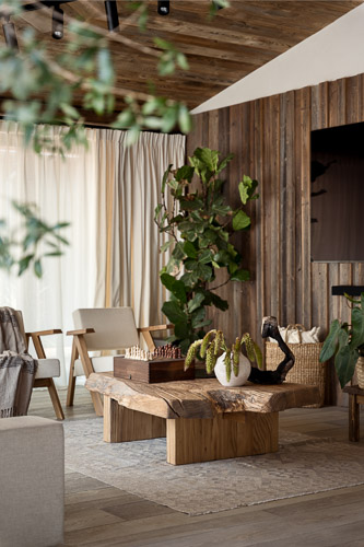 przytulny salon z dodatkami z naturalnych materialow, duzo roslin i piekny drewniany stolik kawowy