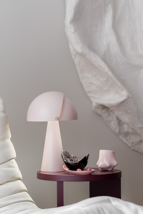 Elegancka i delikatna jasno rozowa lampka na udekorowanym, bordowym stoliku